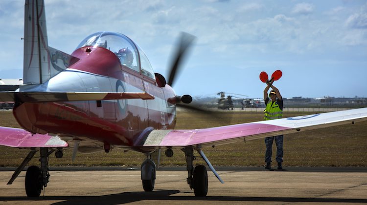 A Royal Australian Air Force PC-9/A aircraft, part of the Roulettes aerobatic display team, is marshalled to a stop after arriving at RAAF Base Townsville for the T150 Defence Force Air Show and Open Day.