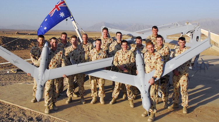 Photo by Corporal Hamish Paterson Caption: Men of the 20th Surveillance and Target Aquisition Regiment proudly display their ScanEagle Unmanned Aerial Vehicles (UAV's) at Camp Holland in Tarin Kowt, Afghanistan. Mid Caption: Mid Caption: The Australian Army’s 20th Surveillance and Target Acquisition Regiment has deployed an Unmanned Aerial Vehicle (UAV) detachment to the main Australian operating base in Tarin Kowt, located in Oruzgan Province, Afghanistan. The ScanEagle is a 24-hour capable system that allows the air vehicle’s operators to pass real-time information to commanders both in the field and in their headquarters. Powered by a whipper-snipper size engine, the improved muffler system makes the aircraft practically silent at altitude. The UAV’s small four-metre wing span and haze-grey paint scheme almost make it invisible, and its high-zoom optics with day and night capability give the air vehicle operators an excellent view of what’s happening on the ground as the ScanEagle cruises along for up to 15 hours.