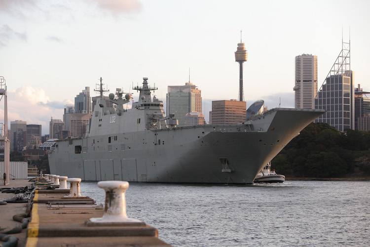 HMAS Canberra rounds the point of Garden Island as the ship sails out of Sydney Harbour.